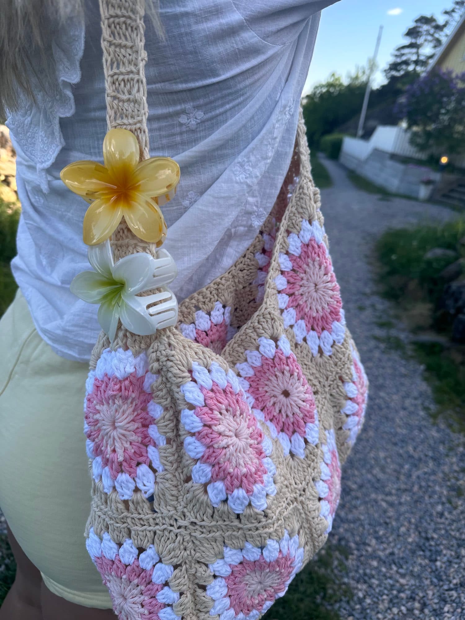 Heklet strandveske med rosa blomster båret over skulderen